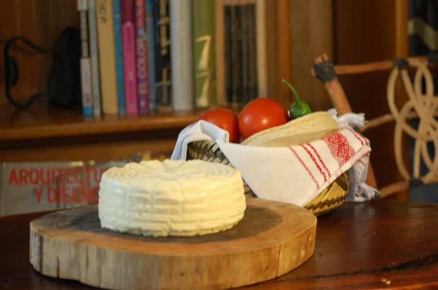 Panela sobre tabla de madera junto a tortillas y jitomates